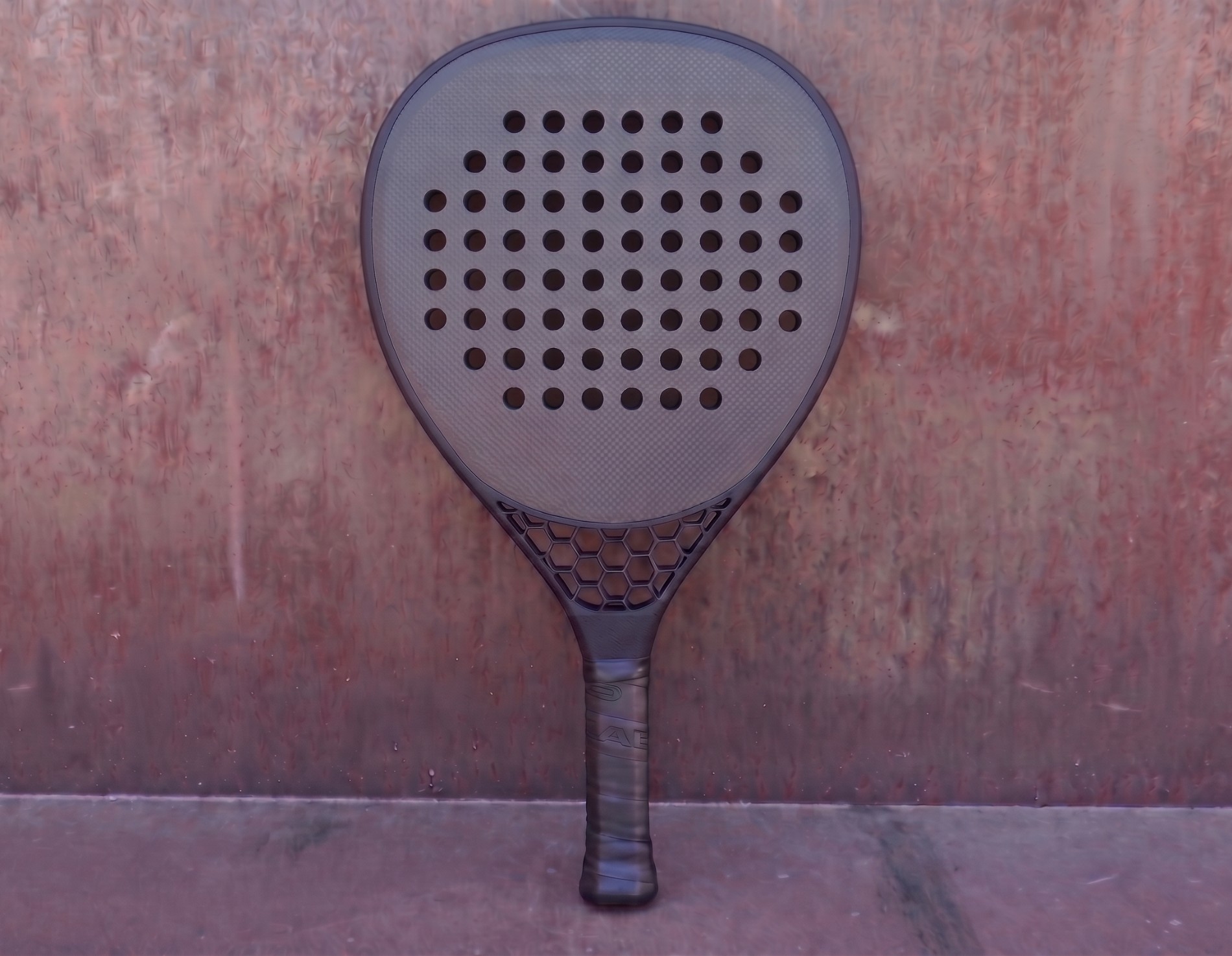 T0 Hex padel racket against rusted steel